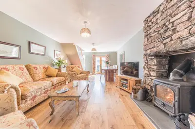a living room with a couch and a stone fireplace at The Black Dog Cottage in Dalton in Furness