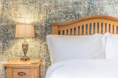 a bedroom with a bed and a lamp on a nightstand at The Black Dog Cottage in Dalton in Furness