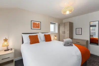a bedroom with a large white bed with orange pillows at Charles Alexander Short Stay - The Gateway in Blackpool