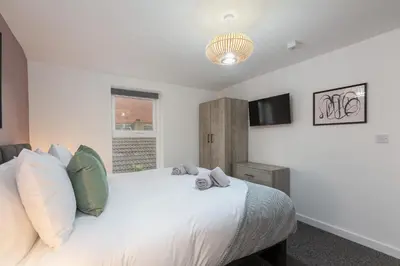a bedroom with a white bed and a television at Charles Alexander Short Stay - The Gateway in Blackpool