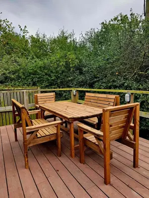 a wooden table and two chairs on a deck at The Woodland Lodge - Wood Fired Hot Tub and Firepit in Hambleton