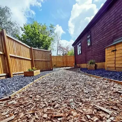 a backyard of a house with a fence at The Woodland Lodge - Wood Fired Hot Tub and Firepit in Hambleton