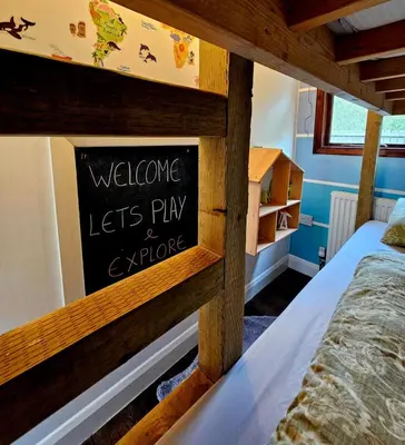 a bedroom with a sign that says welcome lets play aswick at The Woodland Lodge - Wood Fired Hot Tub and Firepit in Hambleton