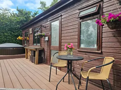 a patio with a table and chairs on a cabin at The Woodland Lodge - Wood Fired Hot Tub and Firepit in Hambleton