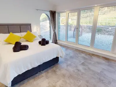 a bedroom with a bed with yellow pillows and windows at Limestone in Ulverston