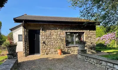 a small stone building with a window in a yard at Locka Old Hall Cottage in Arkholme