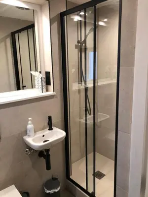 a bathroom with a glass shower and a sink at Locka Old Hall Cottage in Arkholme