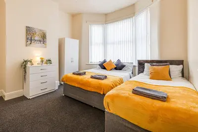 a bedroom with two beds and a dresser and a window at Ursula Sparkle Stays in Liverpool