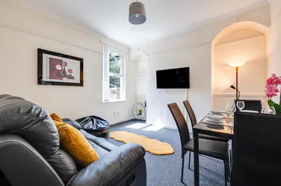 a living room with a leather couch and a table at Ursula Sparkle Stays in Liverpool