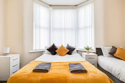 a bedroom with a large bed with an orange blanket at Ursula Sparkle Stays in Liverpool