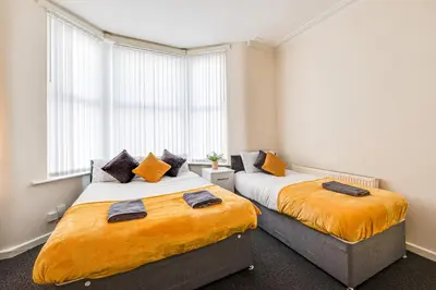 a bedroom with two beds with orange sheets at Ursula Sparkle Stays in Liverpool