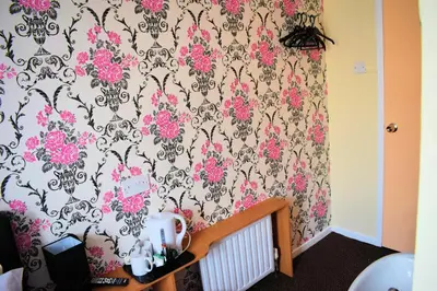 a bedroom with a wallpaper with pink flowers on it at The Clarendon Hotel in Blackpool