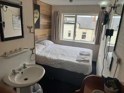 a bathroom with a sink and a bed in a room at The Clarendon Hotel in Blackpool