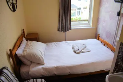 a bedroom with a bed with white sheets and a window at The Clarendon Hotel in Blackpool