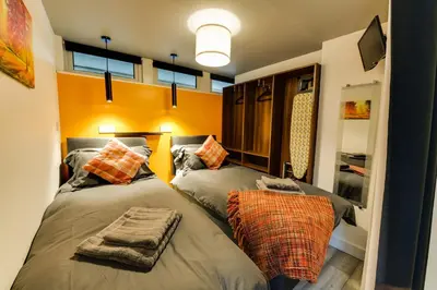 two beds in a room with orange walls and windows at 1 Bedroom Swinley Apartment l Free Parking l Wigan Royal Infirmary l Haigh Hall l Central Location in Wigan