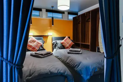 two beds in a room with blue curtains at 1 Bedroom Swinley Apartment l Free Parking l Wigan Royal Infirmary l Haigh Hall l Central Location in Wigan