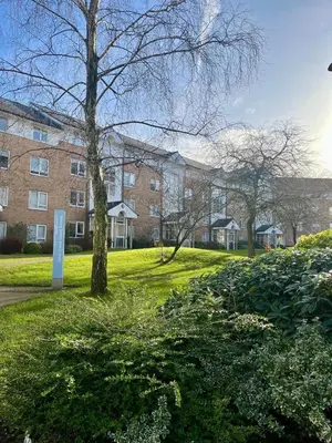 a brick building with a tree in the grass at Lancaster University in Lancaster