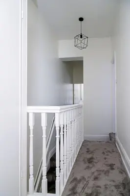 a hallway with a white staircase with a light fixture at Hibbert Galore in Barrow in Furness
