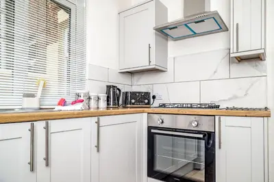 a kitchen with white cabinets and a stove top oven at Hibbert Galore in Barrow in Furness
