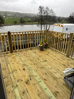 a wooden deck with a fence and flowers on it at 5 Lake View, Barrow, Clitheroe - in the heart of the Ribble Valley in Pendleton