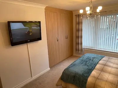 a bedroom with a bed and a tv on the wall at 'Sounion' - Fabulous, spacious modern house with large private garden in Leafy Lytham in Lytham St Annes