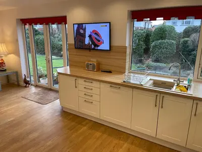 a kitchen with a sink and a tv on a wall at 'Sounion' - Fabulous, spacious modern house with large private garden in Leafy Lytham in Lytham St Annes