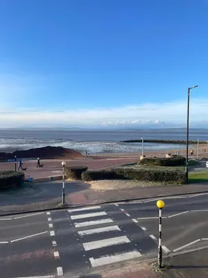 an empty street with a crosswalk in front of the ocean at The Croston promenade balcony apartment- Morecambe central promenade, beach front and sea views in Morecambe