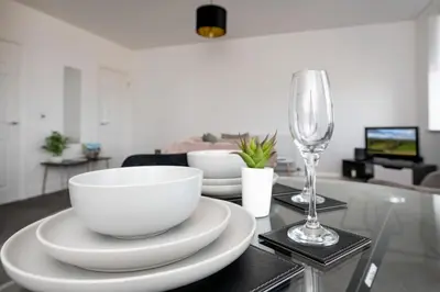 a table with bowls and plates and a wine glass at The Croston promenade balcony apartment- Morecambe central promenade, beach front and sea views in Morecambe