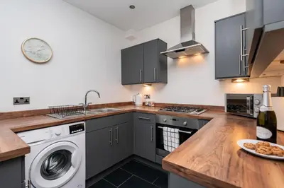 a kitchen with a washing machine and a washer at The Croston promenade balcony apartment- Morecambe central promenade, beach front and sea views in Morecambe