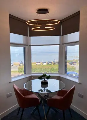 a dining room with a table and two chairs and a window at Eden Retreats Serviced Apartments in Morecambe