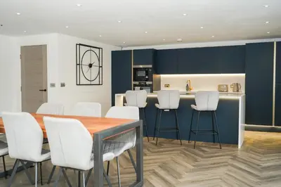 a kitchen with blue cabinets and white stools at NOVU Apartments Duke Street Liverpool in Liverpool