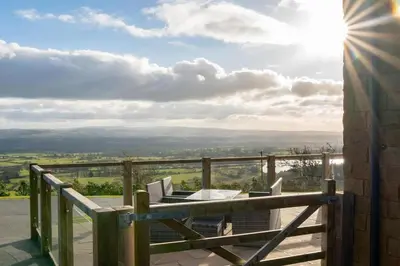 a balcony with a table and chairs and the sun at Pendle View Sleeps 8 with Hot Tub in Longridge