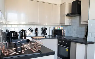 a kitchen with white cabinets and a dish drying rack at Withnell Stays - Apartment Two in Blackpool