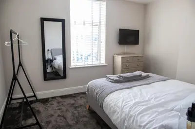 a bedroom with a bed and a mirror and a dresser at Withnell Stays - Apartment Two in Blackpool