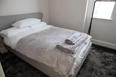 a bed with white sheets and a towel on it at Withnell Stays - Apartment Two in Blackpool