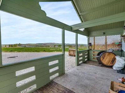 a green covered porch with a large window and a barrel at Pendle View Lodge in Altham