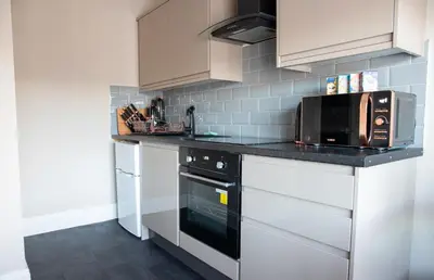 a kitchen with white cabinets and a black microwave at Withnell Stays - Apartment Three in Blackpool