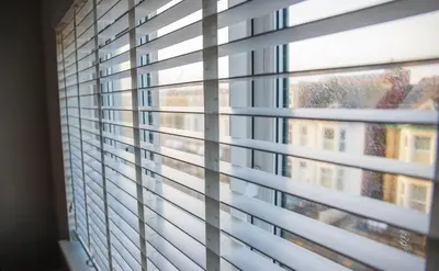 a window with blinds looking out at a building at Withnell Stays - Apartment Three in Blackpool