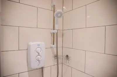 a shower with a shower head on a white tiled wall at Withnell Stays - Apartment Three in Blackpool