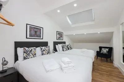 a bedroom with a large white bed and a chair at Concert Square Apartments By Happy Days in Liverpool