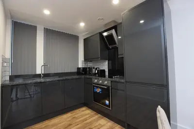 a kitchen with black cabinets and a sink at Concert Square Apartments By Happy Days in Liverpool