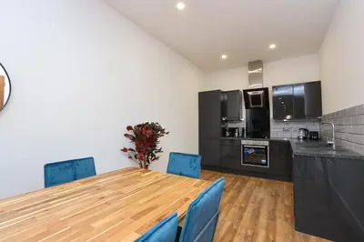 a kitchen with a wooden table and blue chairs at Concert Square Apartments By Happy Days in Liverpool