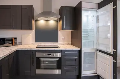 a kitchen with black cabinets and an open refrigerator at Cavern Quarter apartments by The Castle Collection in Liverpool
