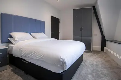 a bedroom with a large bed with a blue headboard at Cavern Quarter apartments by The Castle Collection in Liverpool