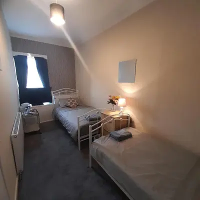 a small room with two beds and a window at Merginn Guest House in Blackpool