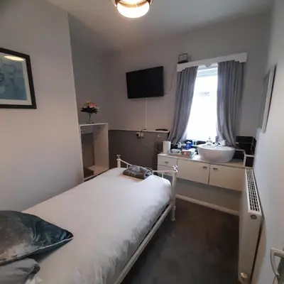 a bedroom with a bed and a sink and a window at Merginn Guest House in Blackpool