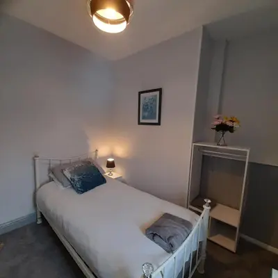 a bedroom with a white bed and a fireplace at Merginn Guest House in Blackpool