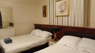 a room with two beds and a mirror at Merginn Guest House in Blackpool