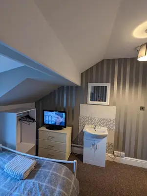 a bedroom with a bed and a sink and a tv at Merginn Guest House in Blackpool
