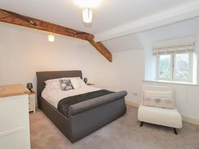 a bedroom with a bed and a chair at 1 The Stables in Grange Over Sands